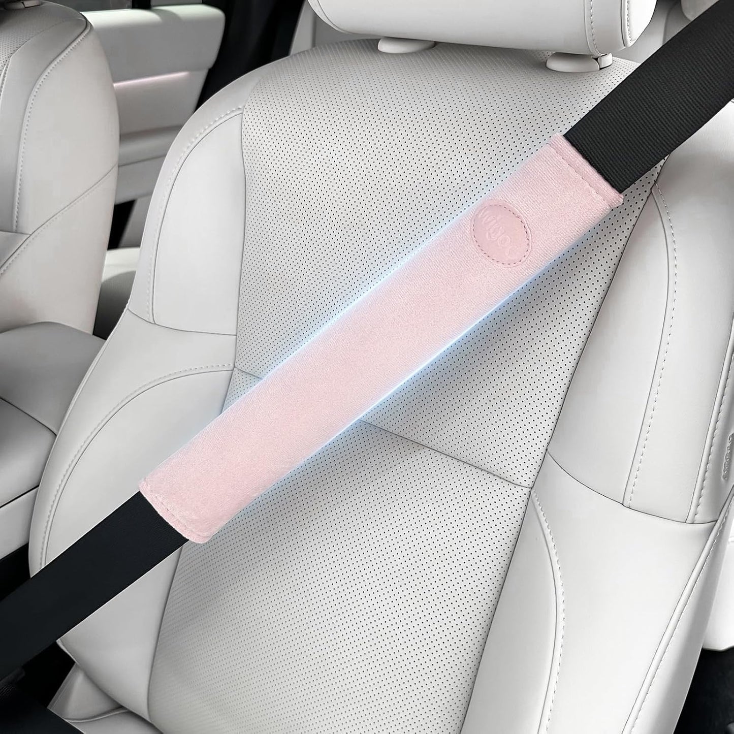 Car seat with a pink and black seat belt cover on a white car interior.