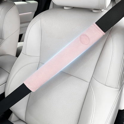Car seat with a pink and black seat belt cover on a white car interior.